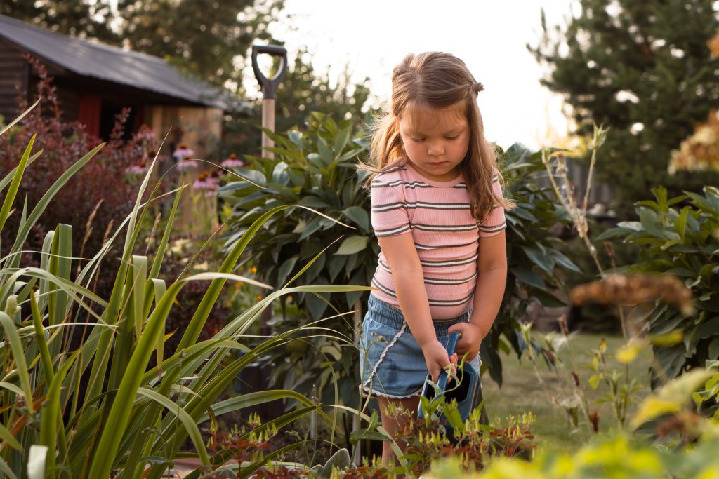 Kind gießt die Pflanzen und Beete im Garten
